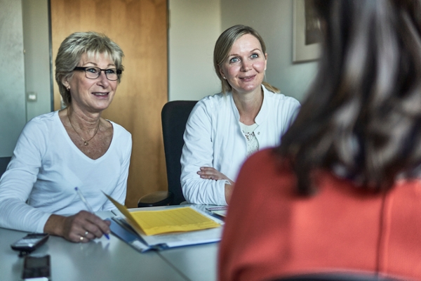 Rehabilitandin sitzt mit Ärztinnen am Tisch im Gespräch Rehabilitandin sitzt mit Ärztinnen am Tisch im Gespräch